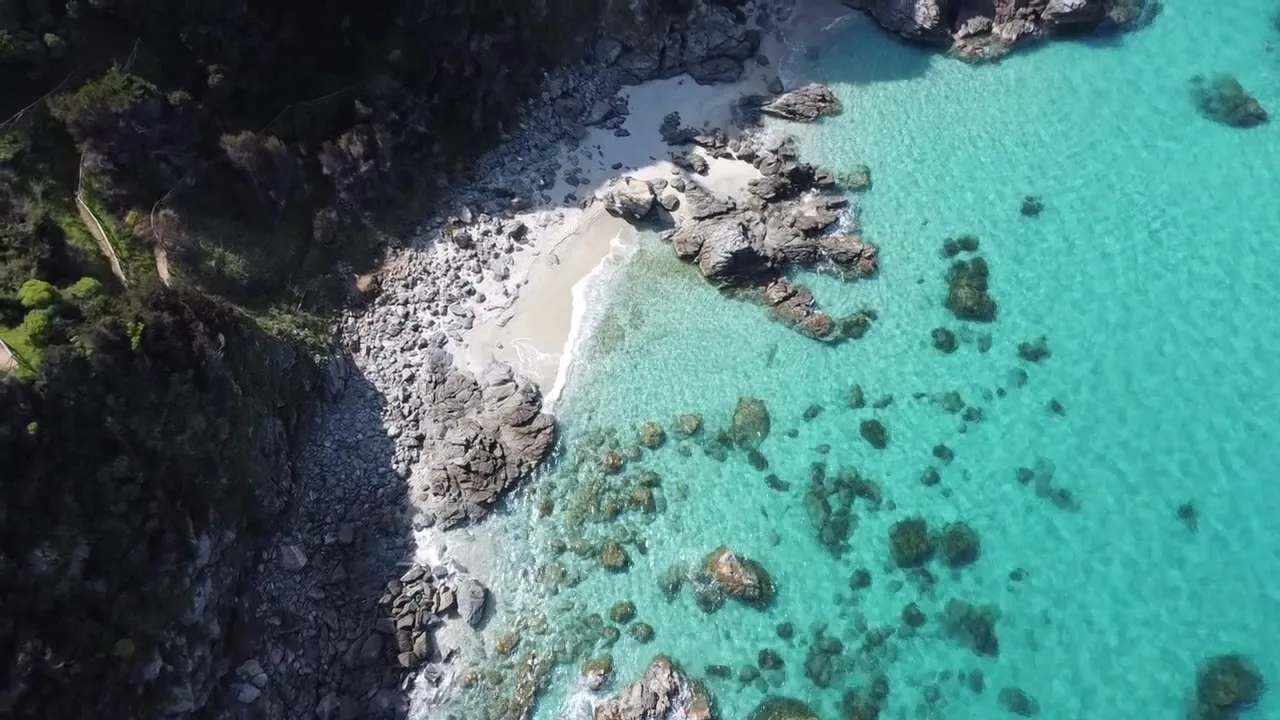 La baia della Marinella vista dal drone: sabbia chiara, scogli e acqua turchese